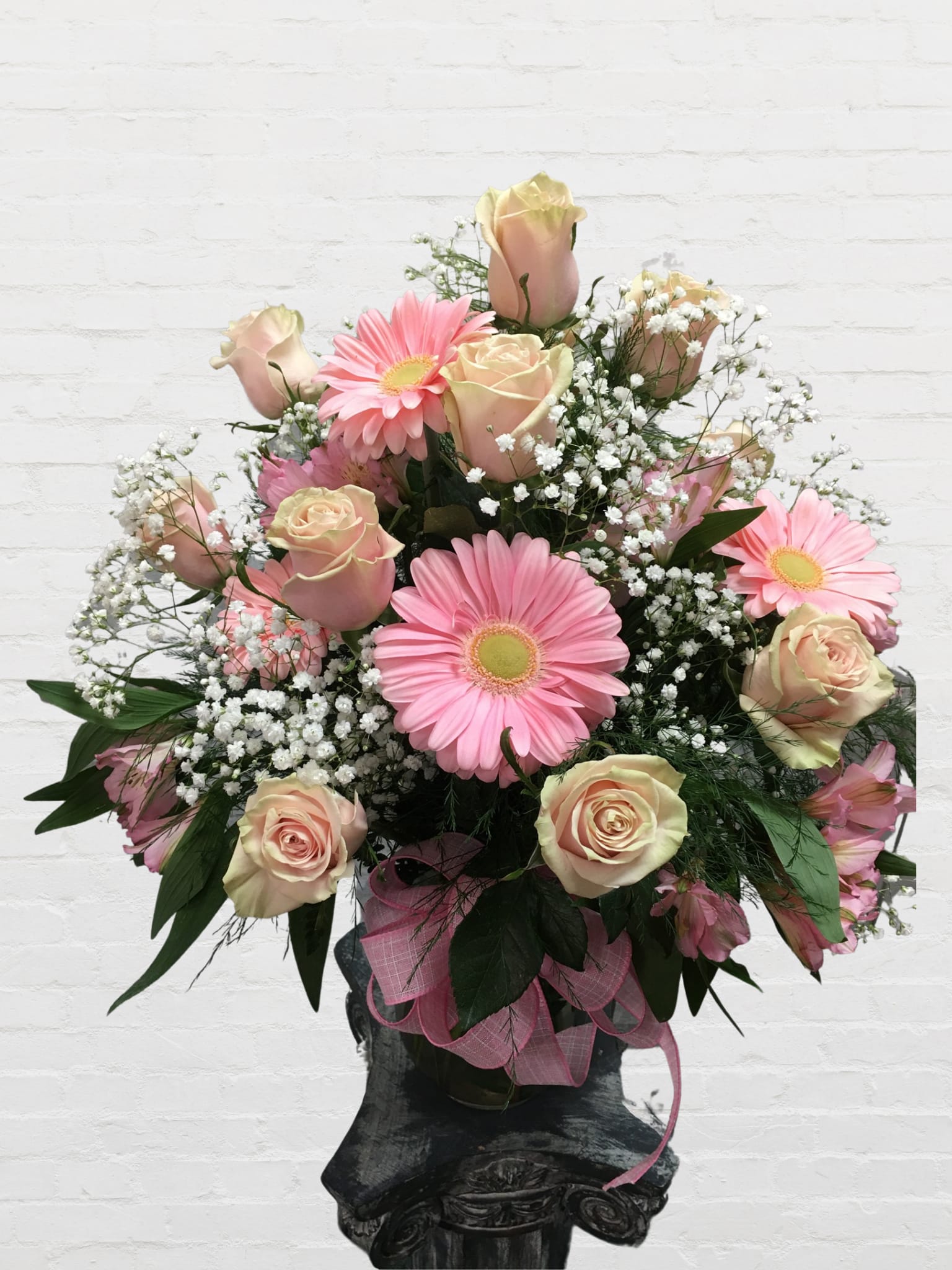Pink gerbera daisies and pale roses in a vase with baby's breath