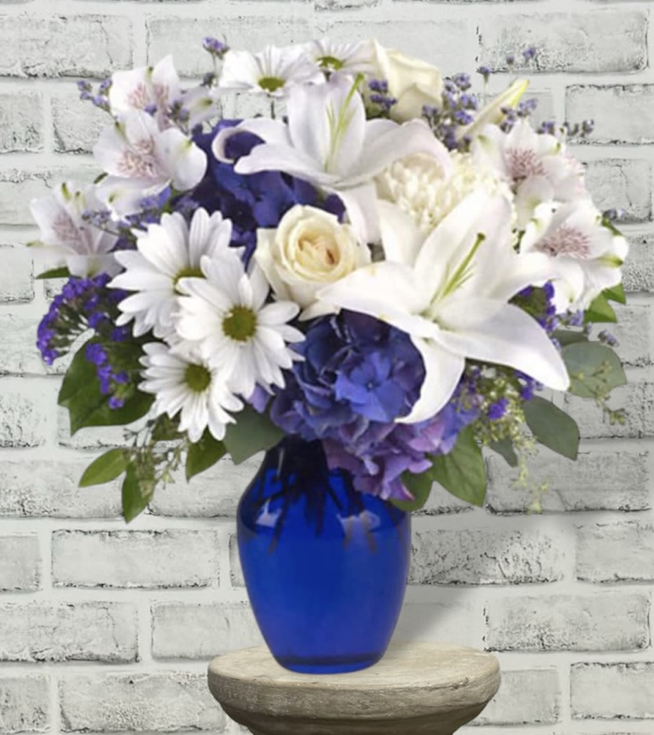 White lilies and daisies in a blue glass vase
