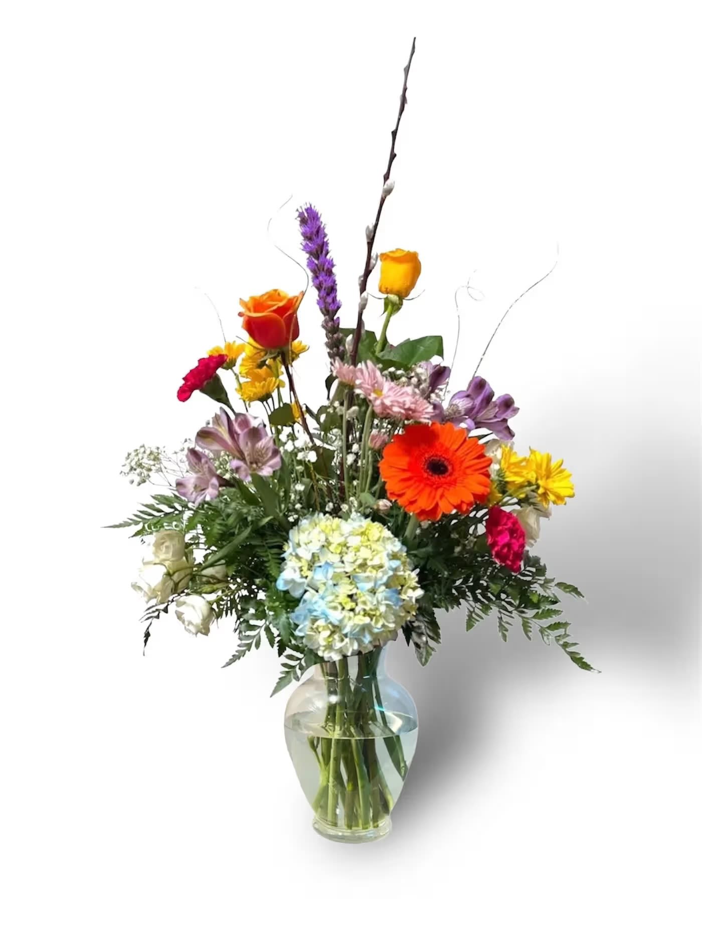 Mixed bouquet in a clear glass vase with bright roses and daisies