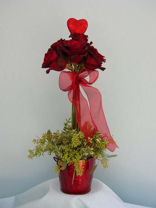 Tall red rose arrangement in a red vase with a sheer ribbon