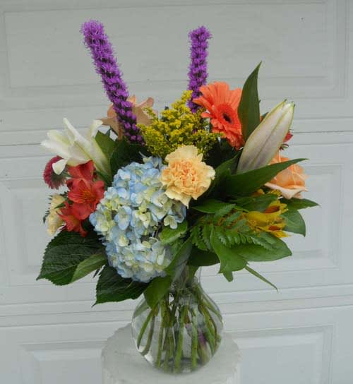 Mixed bouquet in a clear glass vase with hydrangea, lilies, and gerbera daisies