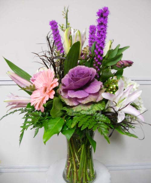 Mixed bouquet with purple, pink, and white flowers in a glass vase