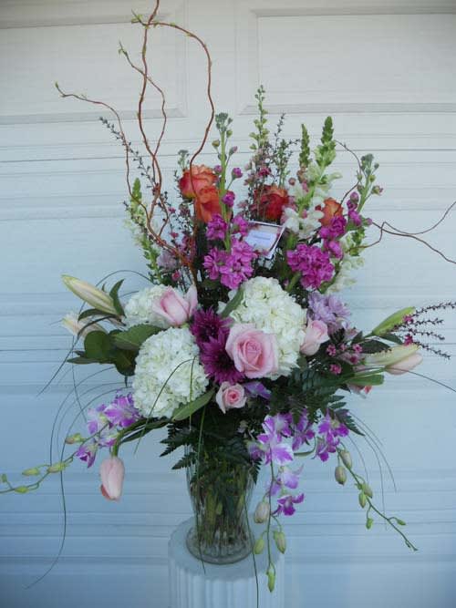 Tall mixed floral arrangement in a glass vase with pink and purple blooms