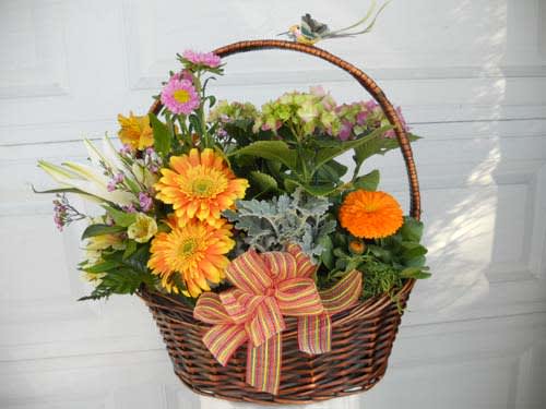 Basket of mixed flowers with a striped ribbon bow