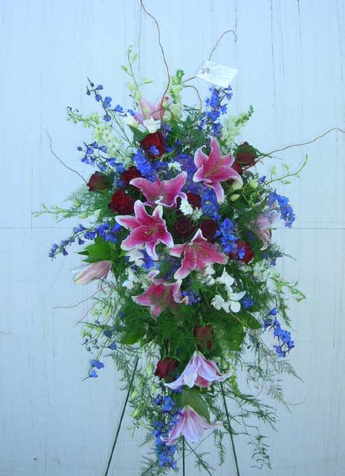 Tall floral spray with pink lilies, red roses, and blue flowers