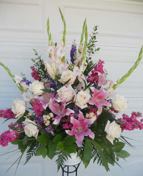 Tall floral arrangement with pink lilies, white roses, and purple accents