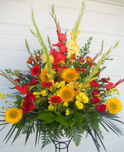 Large arrangement of red and yellow flowers in a white container