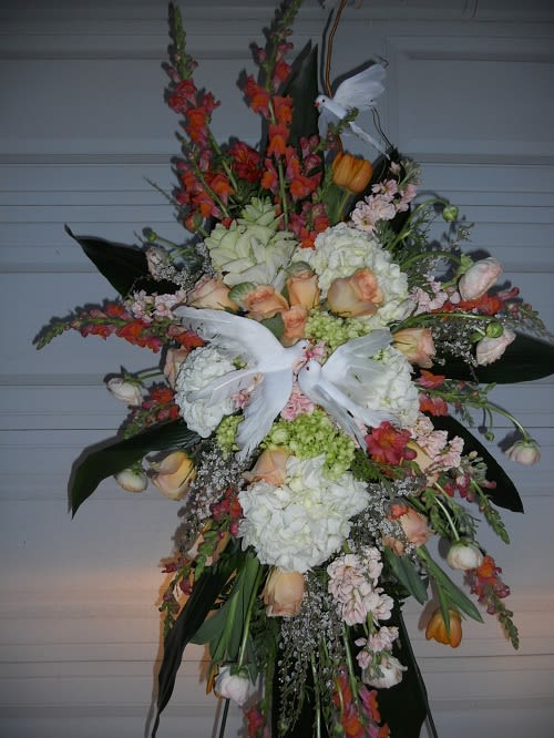 Large standing floral spray with white doves and peach, white, and orange flowers