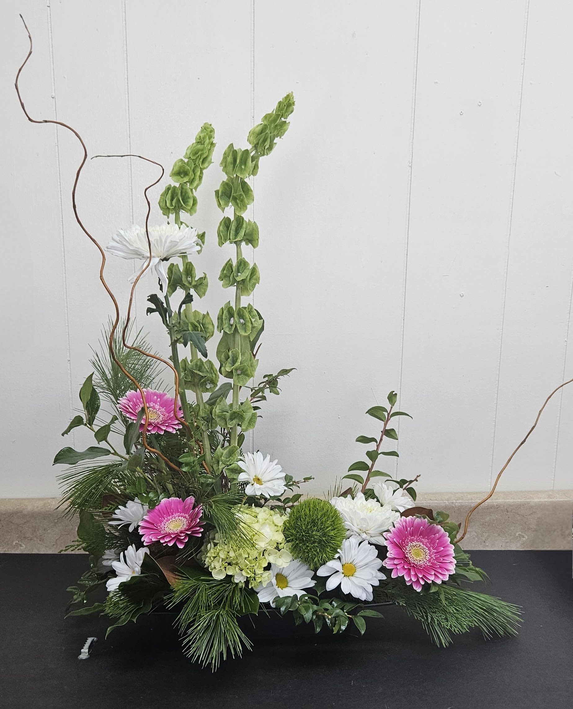 Low floral arrangement with pink gerberas, white daisies, and green blooms