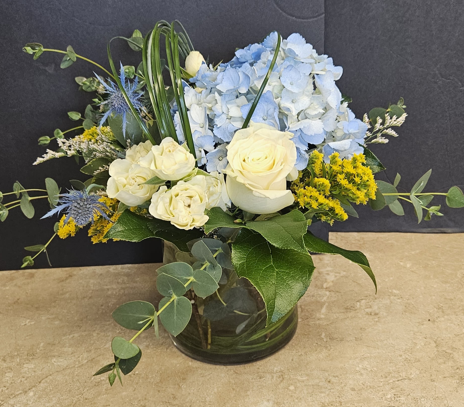 Blue hydrangeas and cream roses in a glass vase