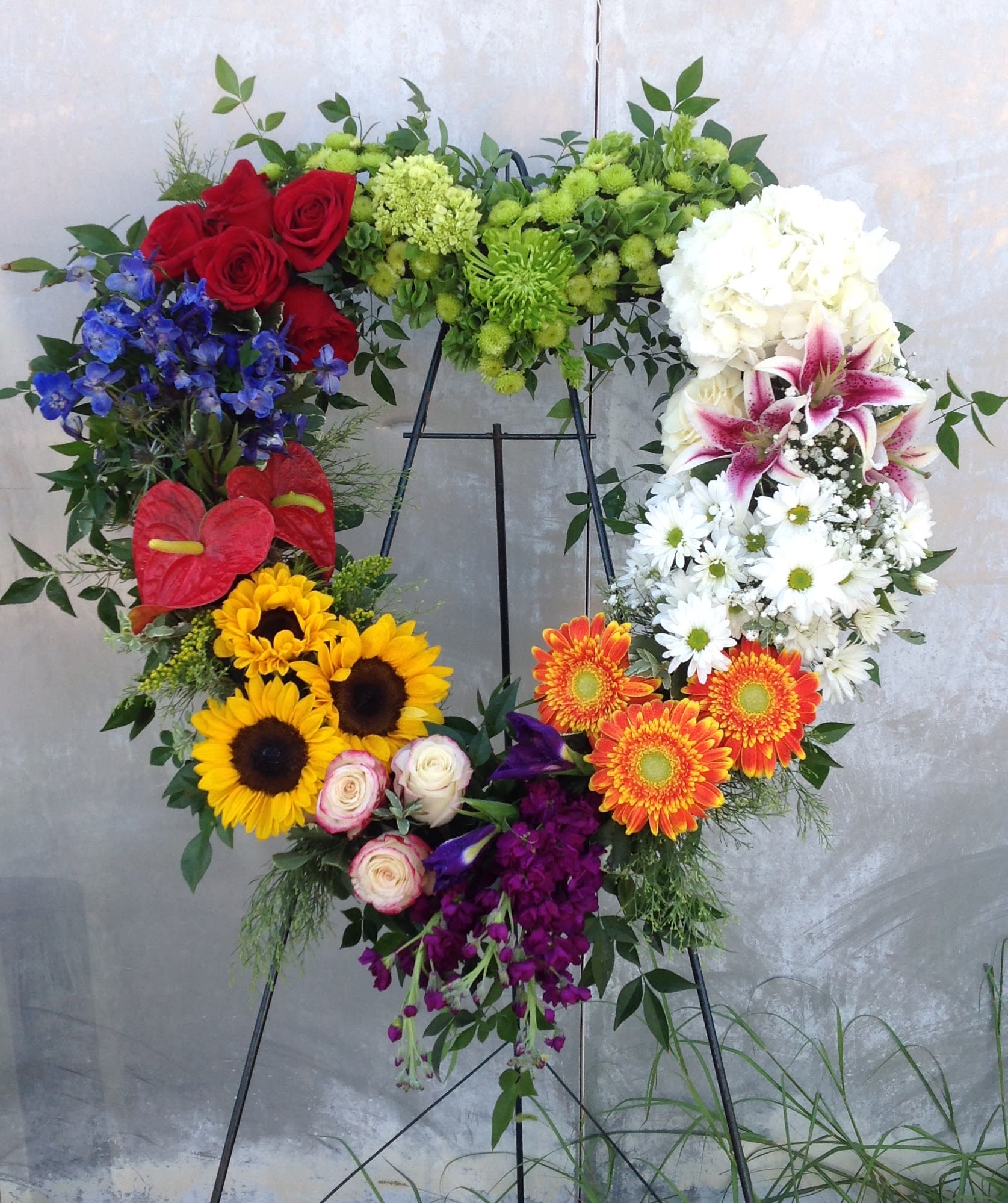 Heart-shaped floral wreath on an easel with mixed bright flowers