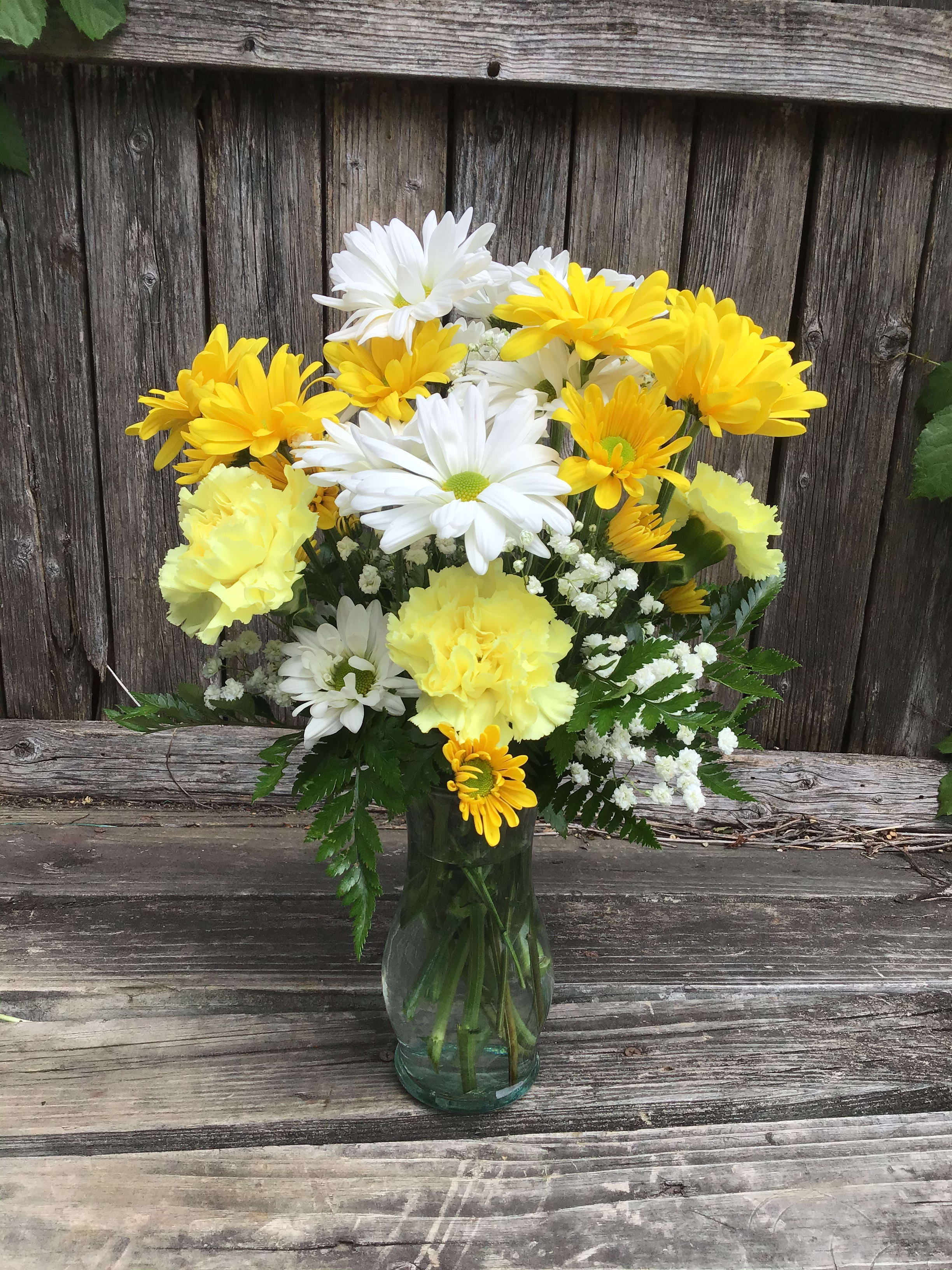 Yellow and white daisy bouquet in a glass vase