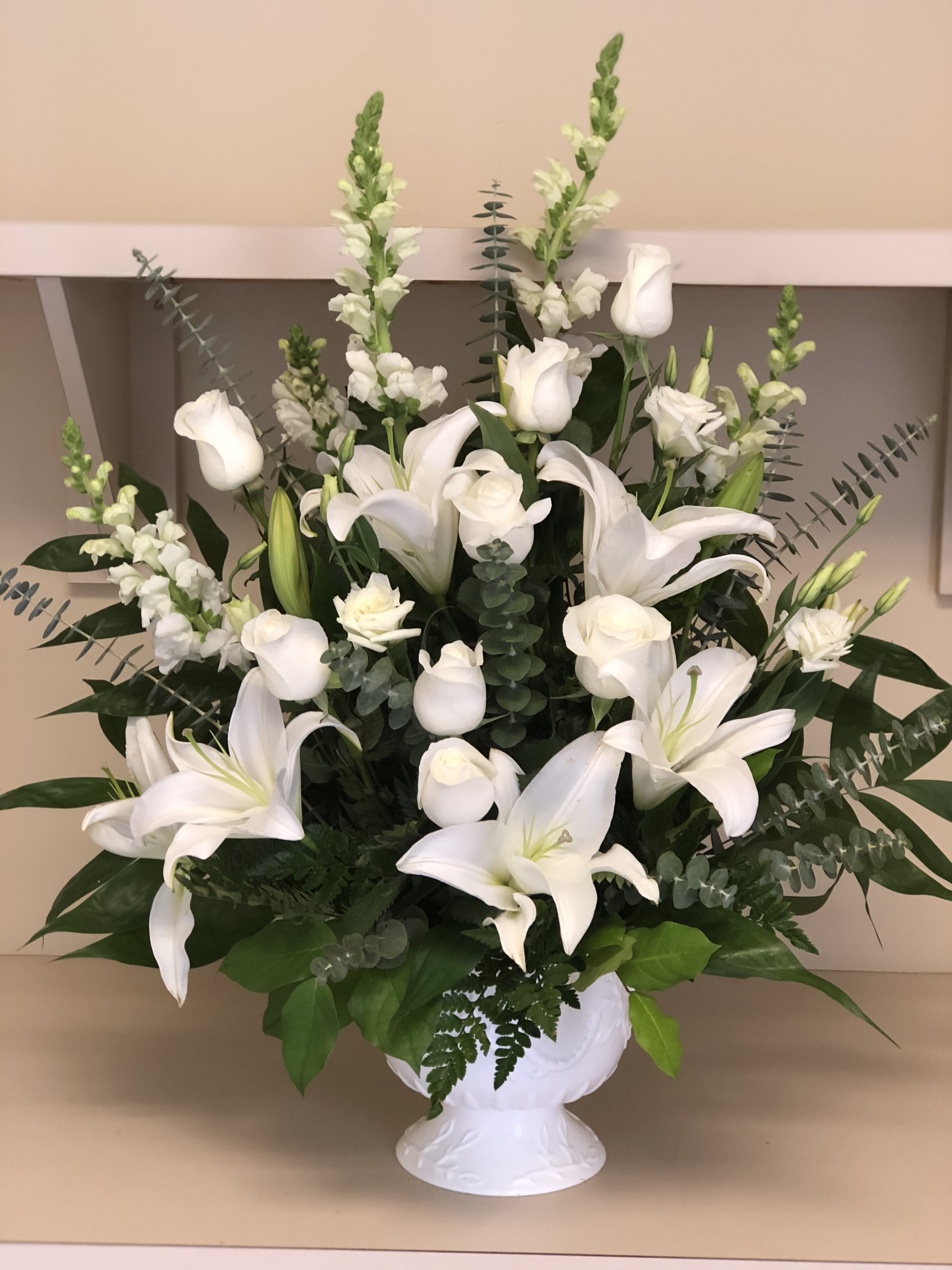 White lilies and roses arranged in a white vase