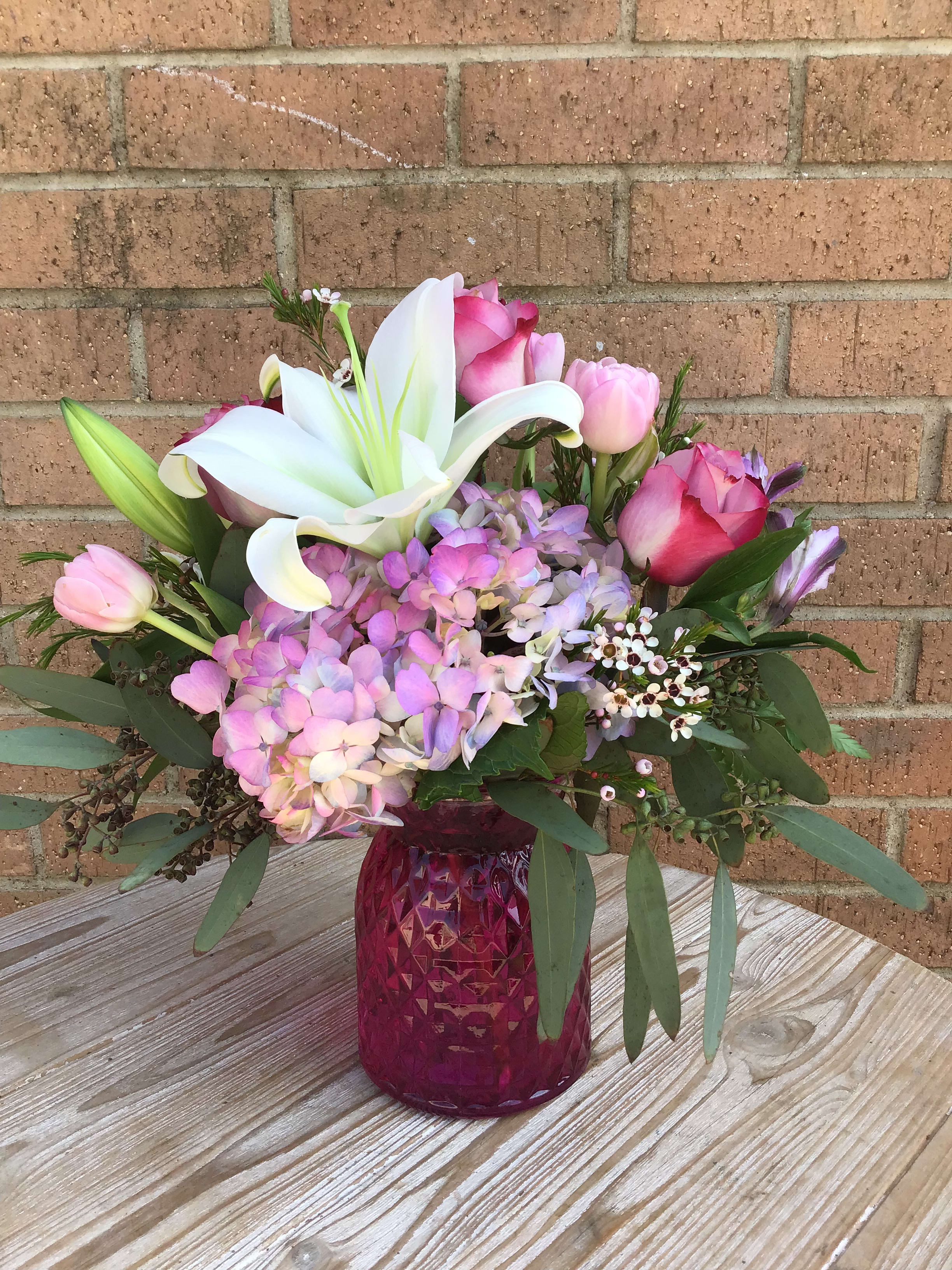 Pink and white floral arrangement in a magenta vase