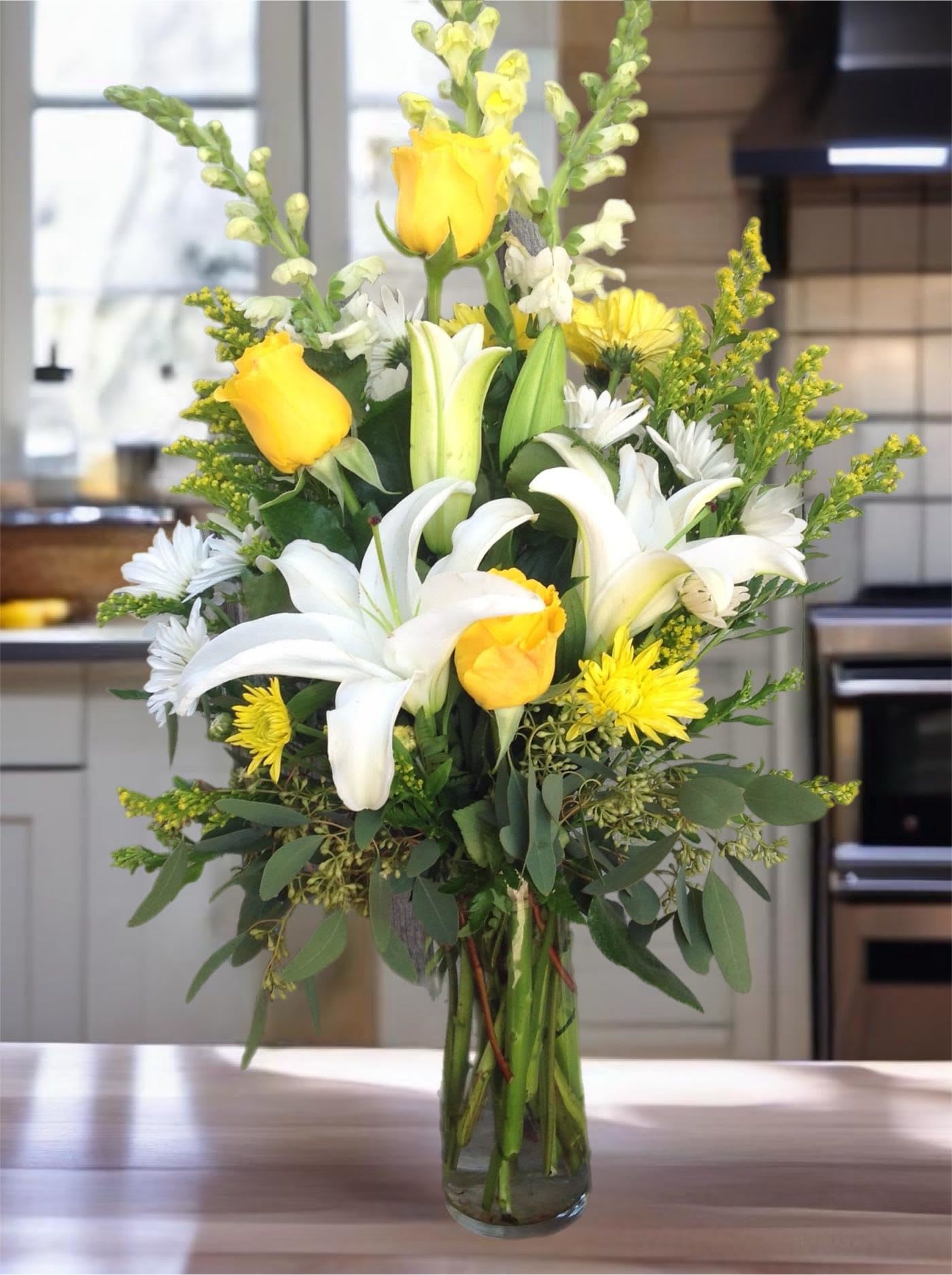 Yellow roses and white lilies in a clear glass vase
