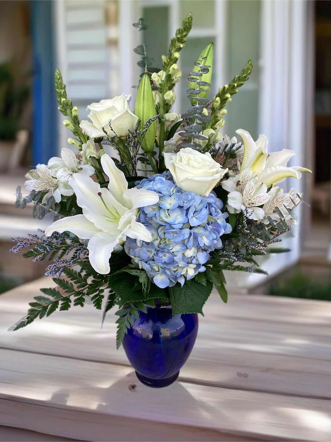 Beautiful in Blue - In this arrangement, the serenity of the color blue along with the purity of intention symbolized by white will let the family know you are sending your calm strength to them during these difficult times. 