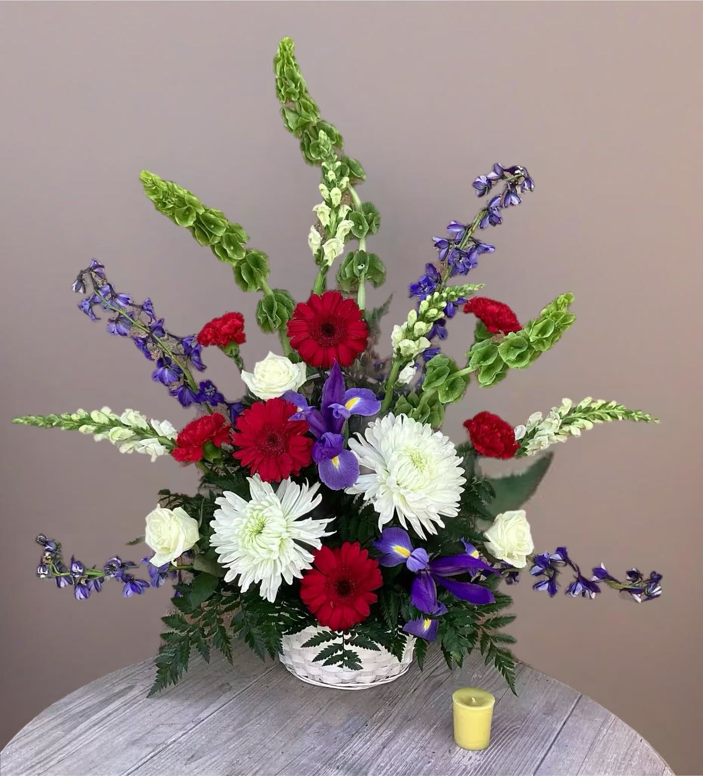 Red, white, and purple flowers in a white basket arrangement