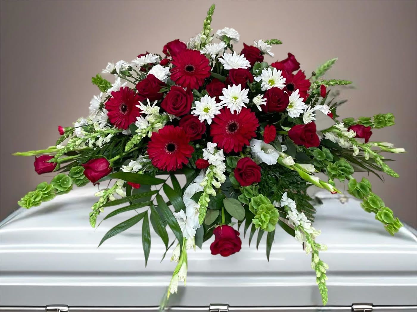 Red and white floral casket spray with roses and daisies