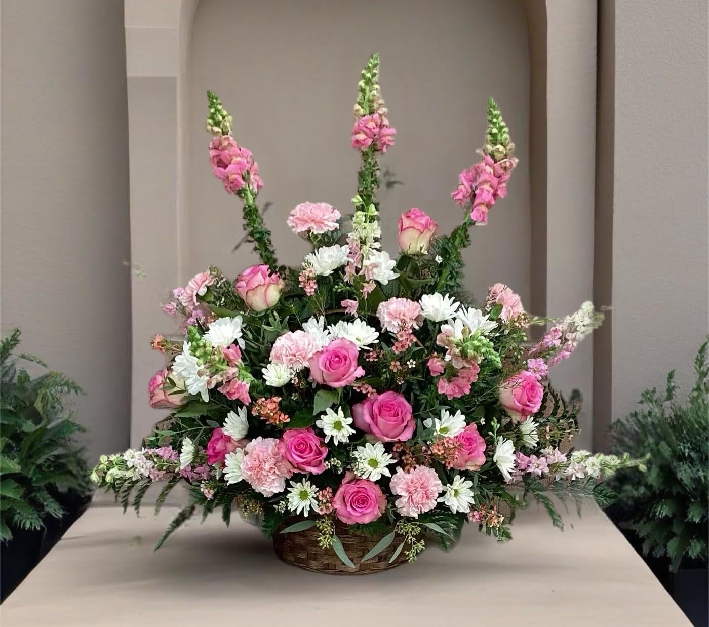 Large basket arrangement of pink roses, carnations, and white daisies