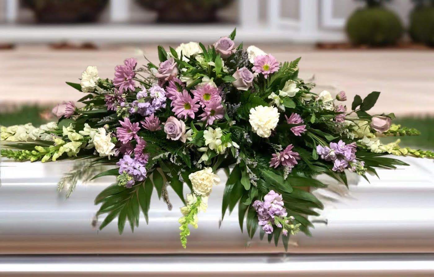 Lavender and white floral casket spray with greenery