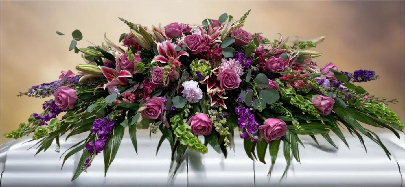 Large purple and pink floral casket spray with roses and lilies