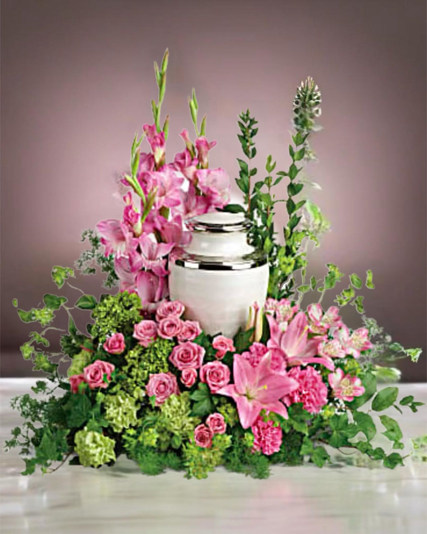 Pink floral arrangement around a white urn with lilies and roses