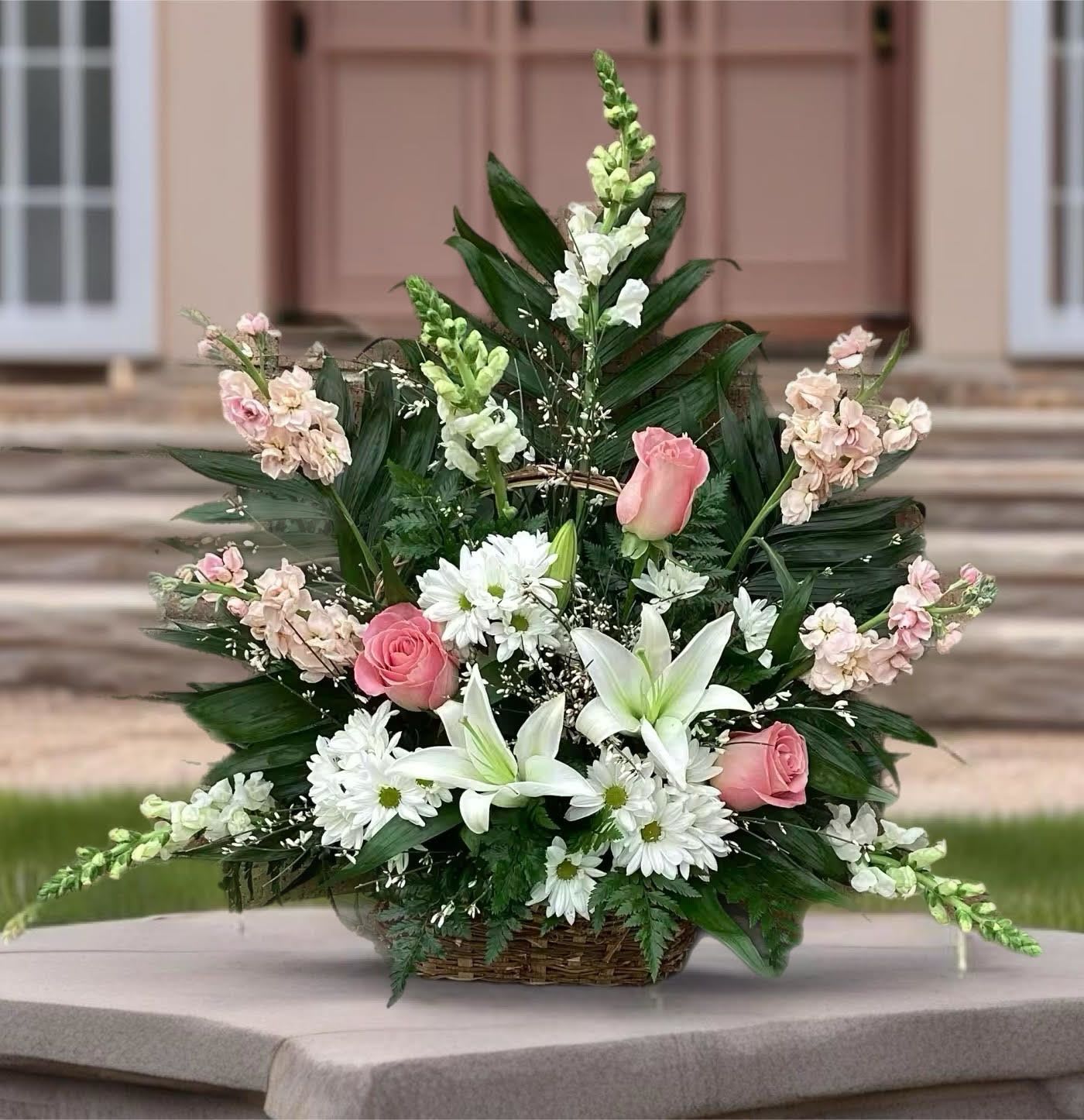 Basket arrangement of pink roses, white lilies, and daisies