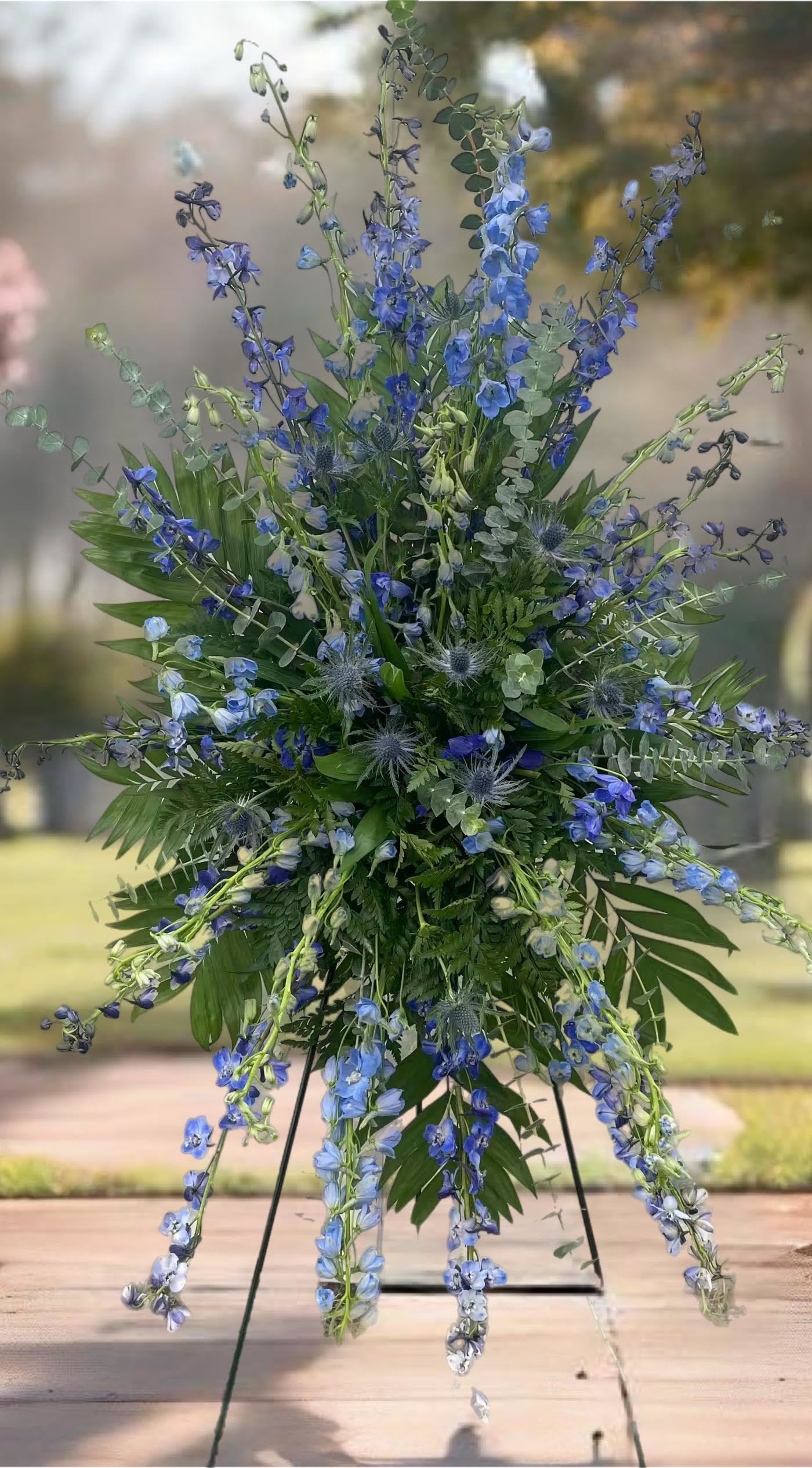 Tall blue floral spray on a stand with mixed greenery