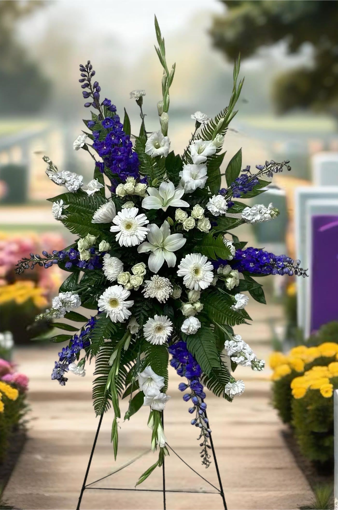 Standing floral spray with white and purple flowers on a metal easel