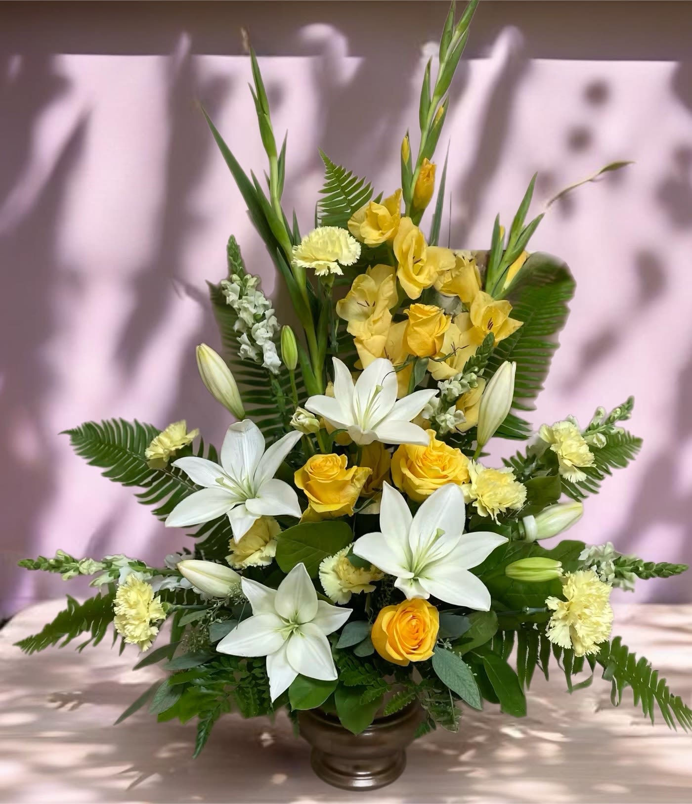 Yellow roses and white lilies arranged in a bronze vase