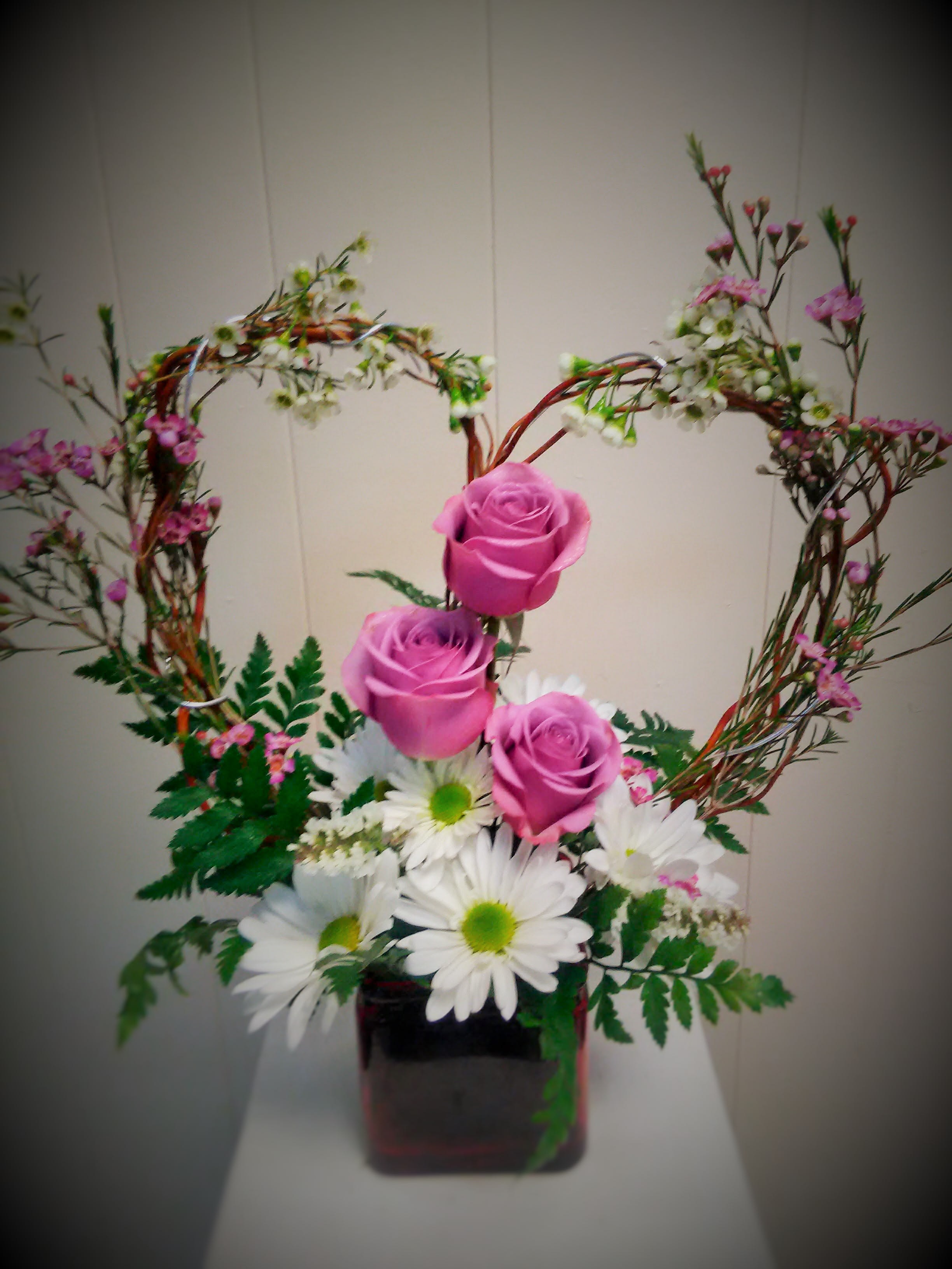 Pink roses and white daisies in a square vase with heart-shaped branches