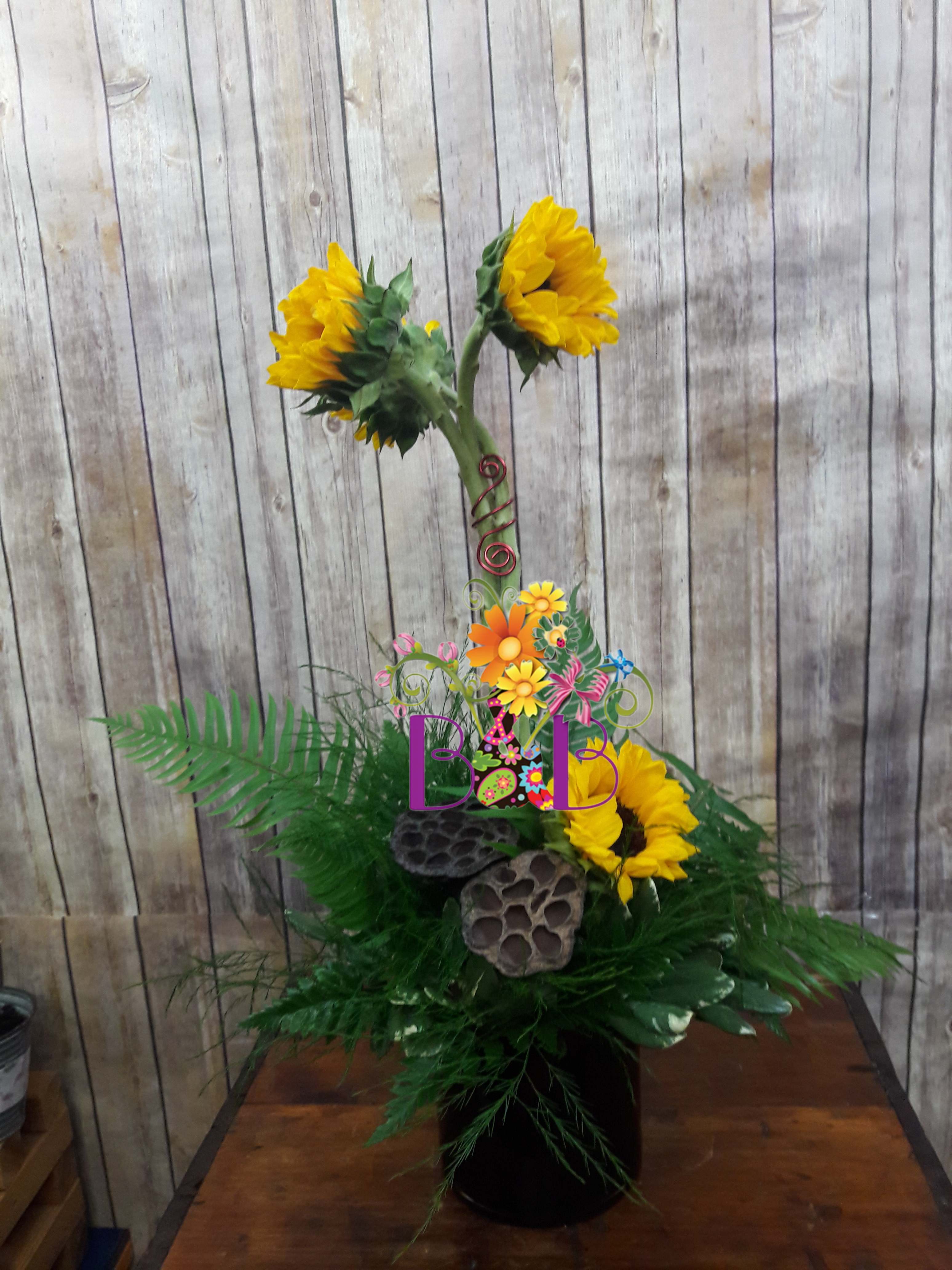 Sunflower arrangement in a black vase with decorative accents