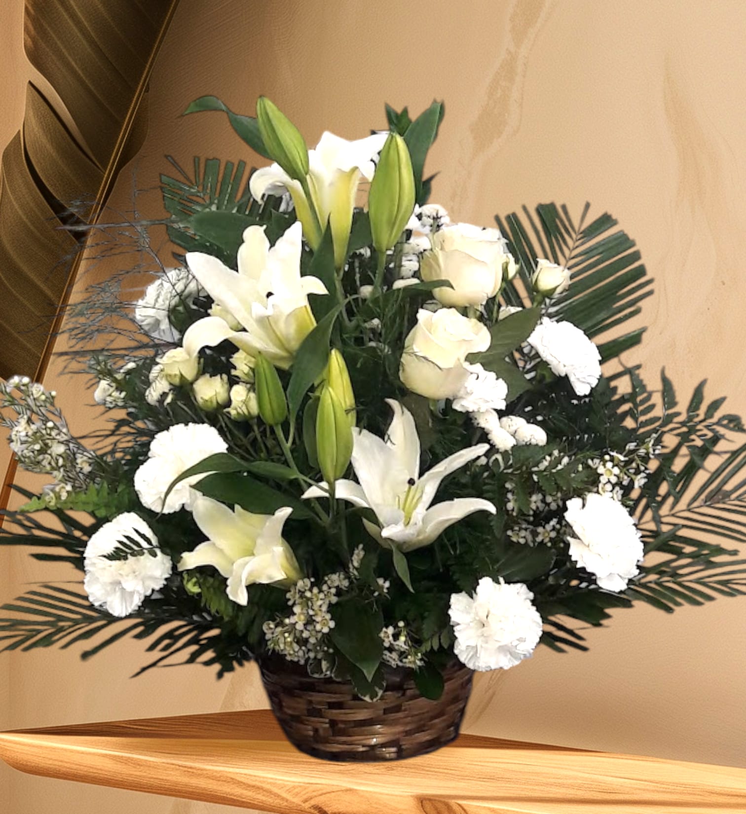 Peaceful Basket of White Lilies - Whether you send this beautiful arrangement to the family home or to the service, all will appreciate its elegance and grace. The contrast of brilliant white blossoms and dazzling greenery create a wonderfully calm and dignified setting.  Gorgeous flowers such as white lilies, carnations and miniature carnations mix with vibrant greens in a handled basket. Simply stunning.