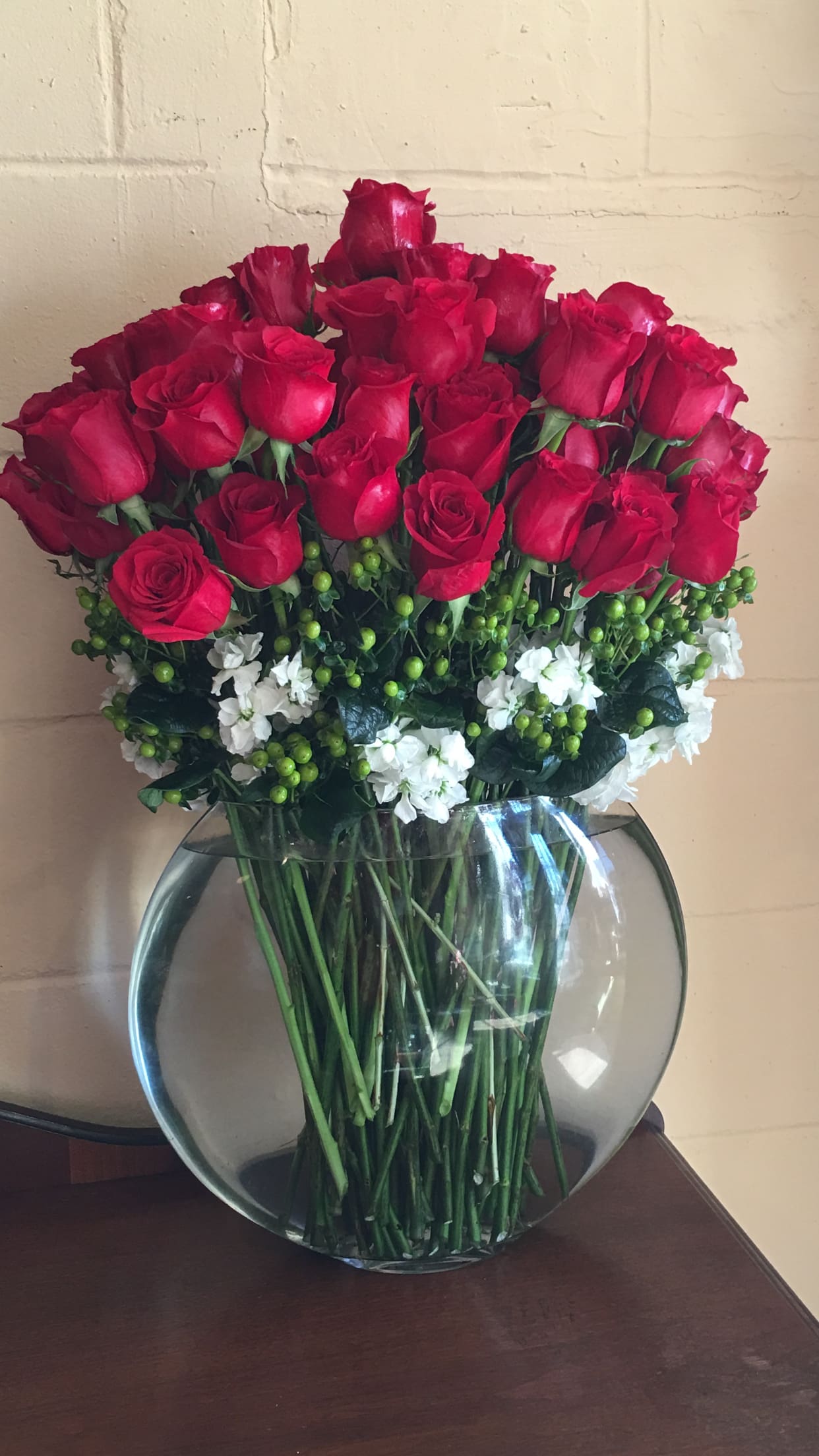 Bouquet of red roses and white flowers in a round glass vase