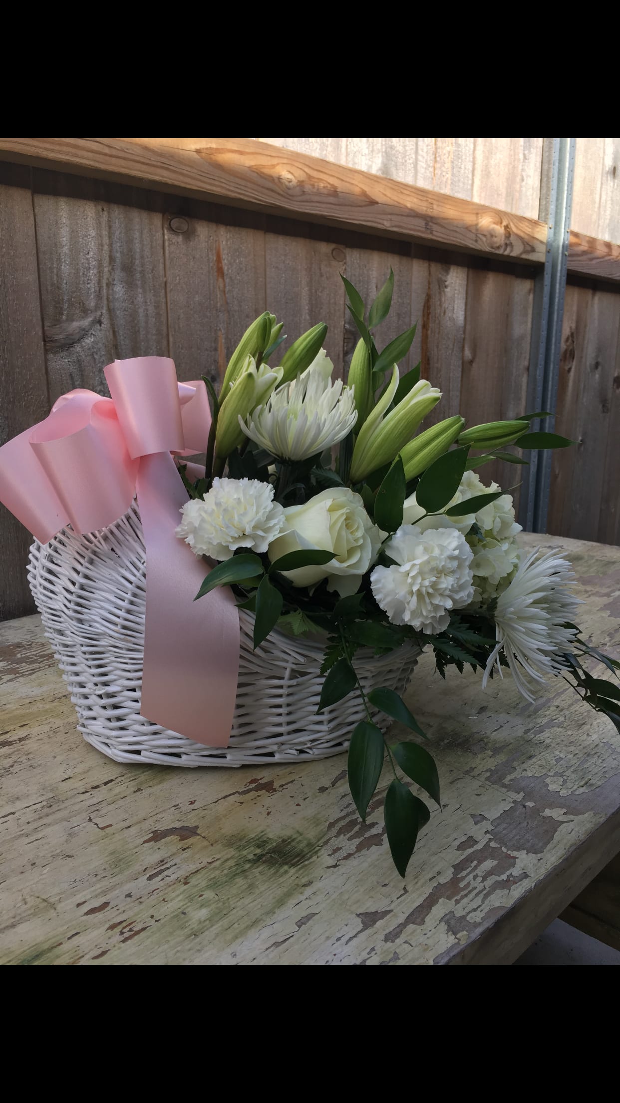 White floral basket with pink ribbon and lilies, roses, and chrysanthemums