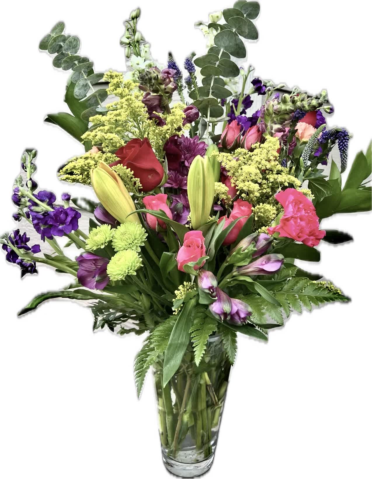 Mixed bouquet of pink, purple, yellow, and red flowers in a clear glass vase