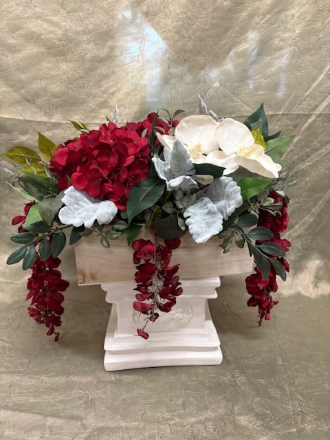 Red and white floral arrangement in a white pedestal container