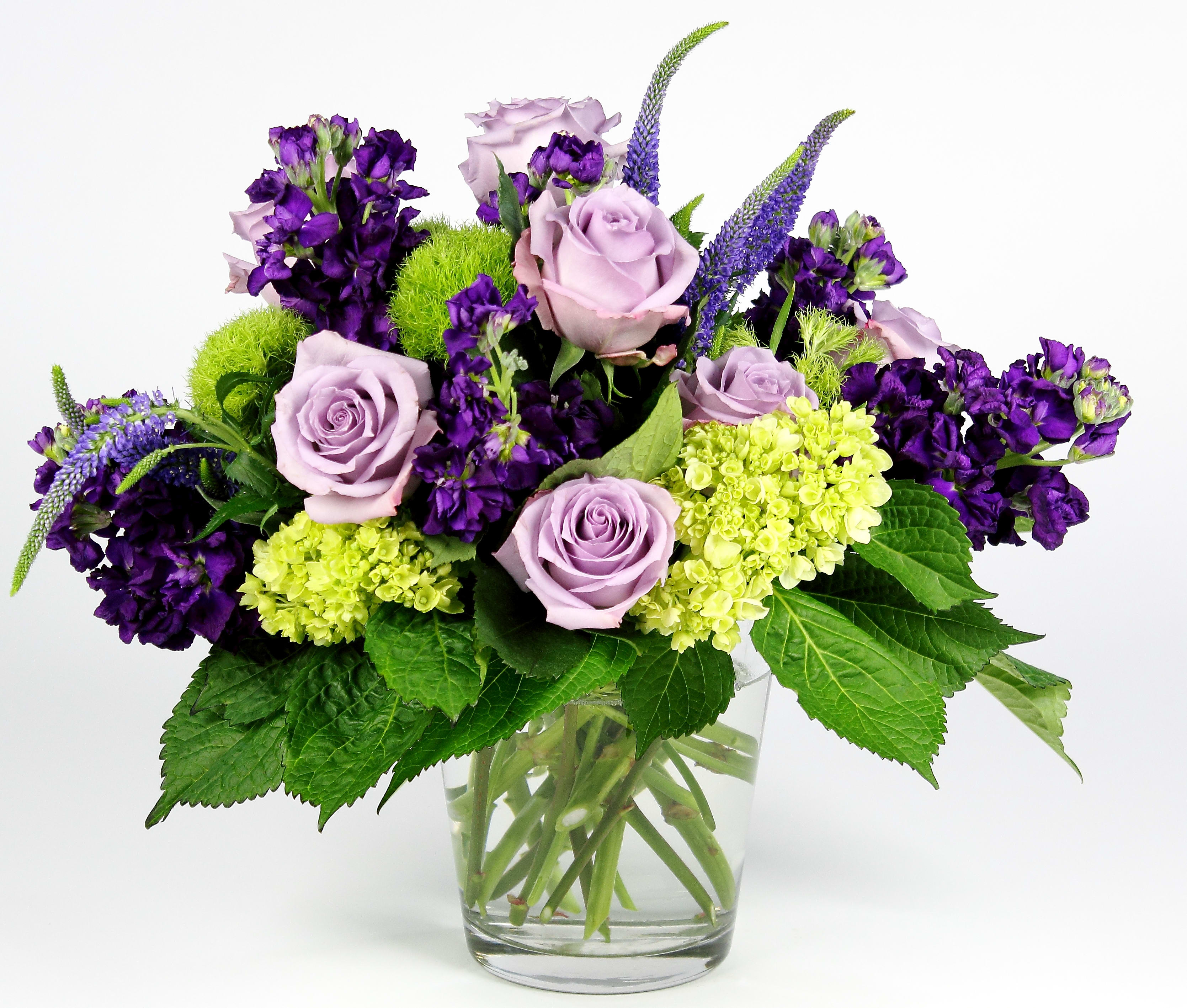 Lavender roses and purple flowers in a clear glass vase