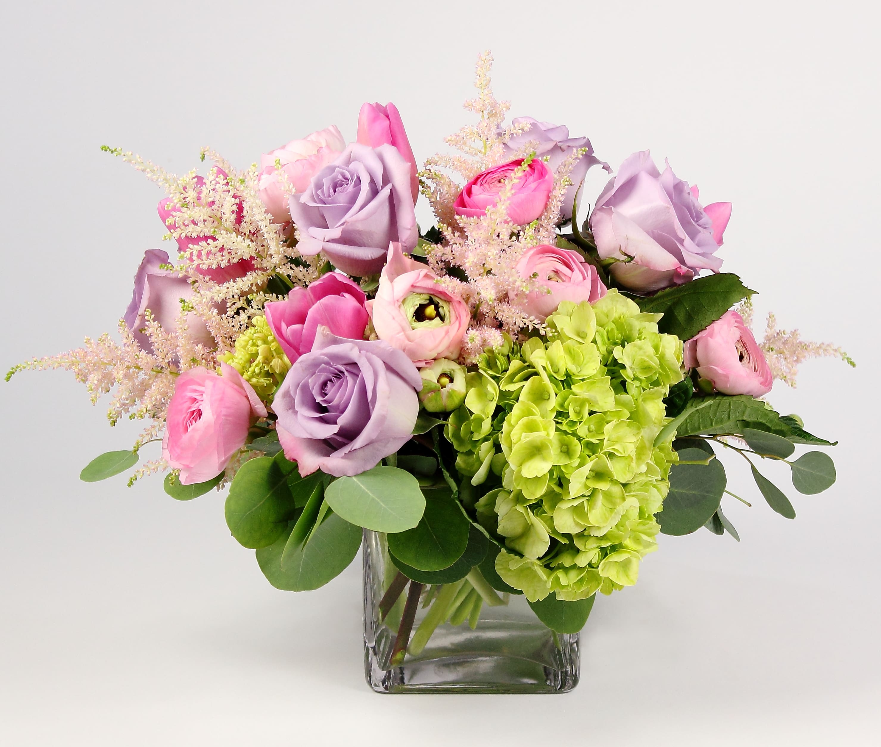 Pink and lavender flowers arranged in a clear glass vase