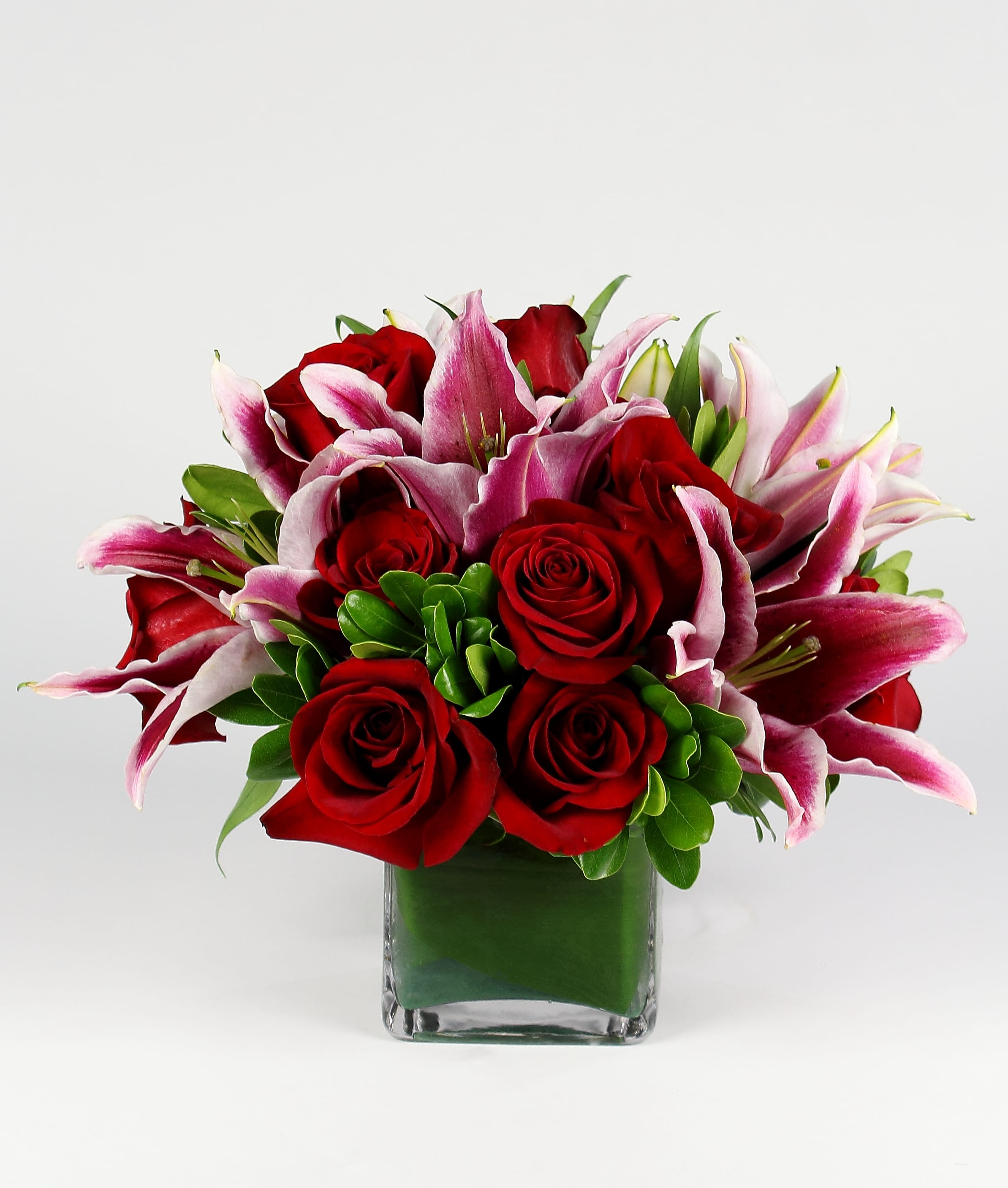 Red roses and pink lilies in a square glass vase