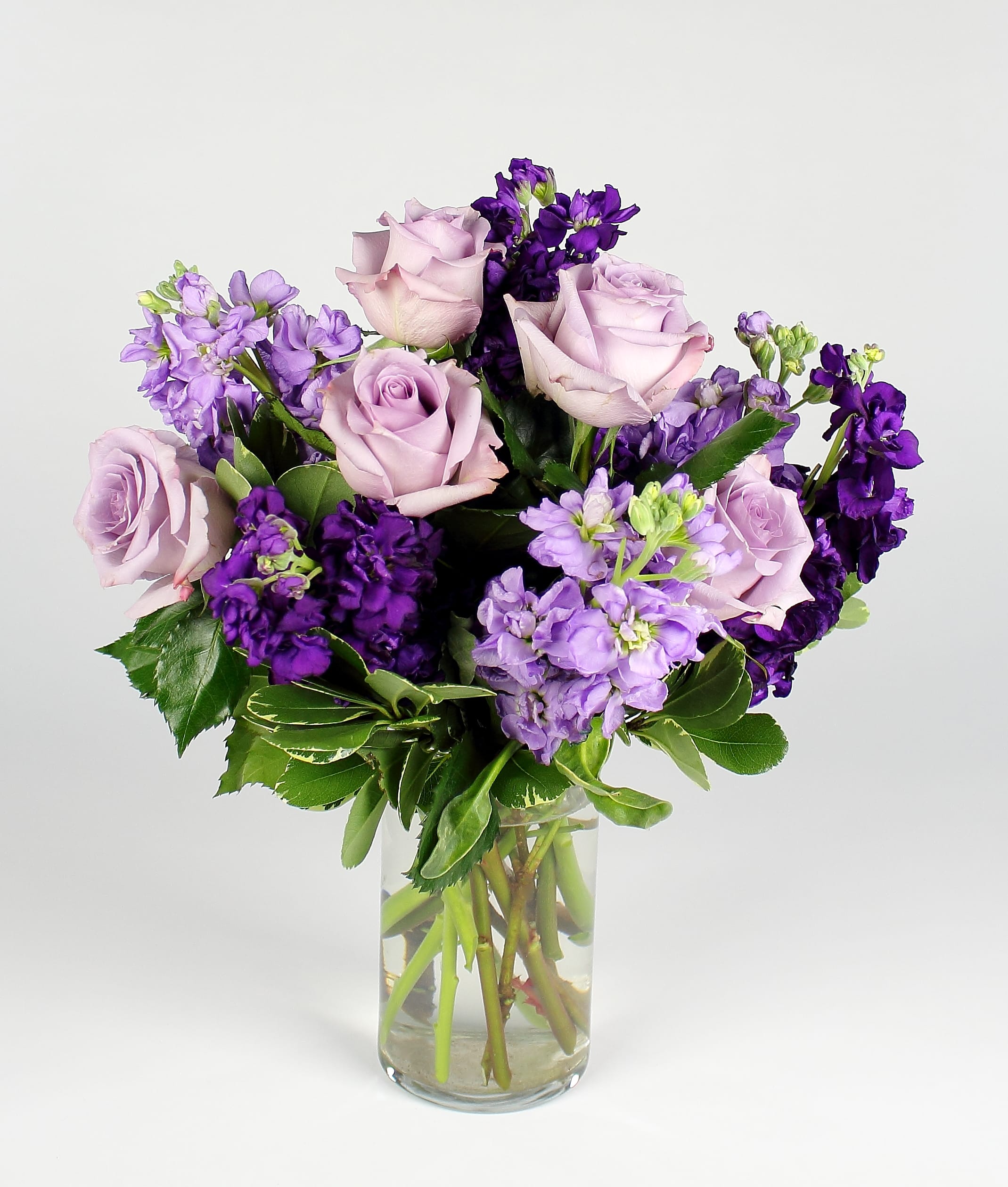 Lavender roses and purple flowers in a clear glass vase