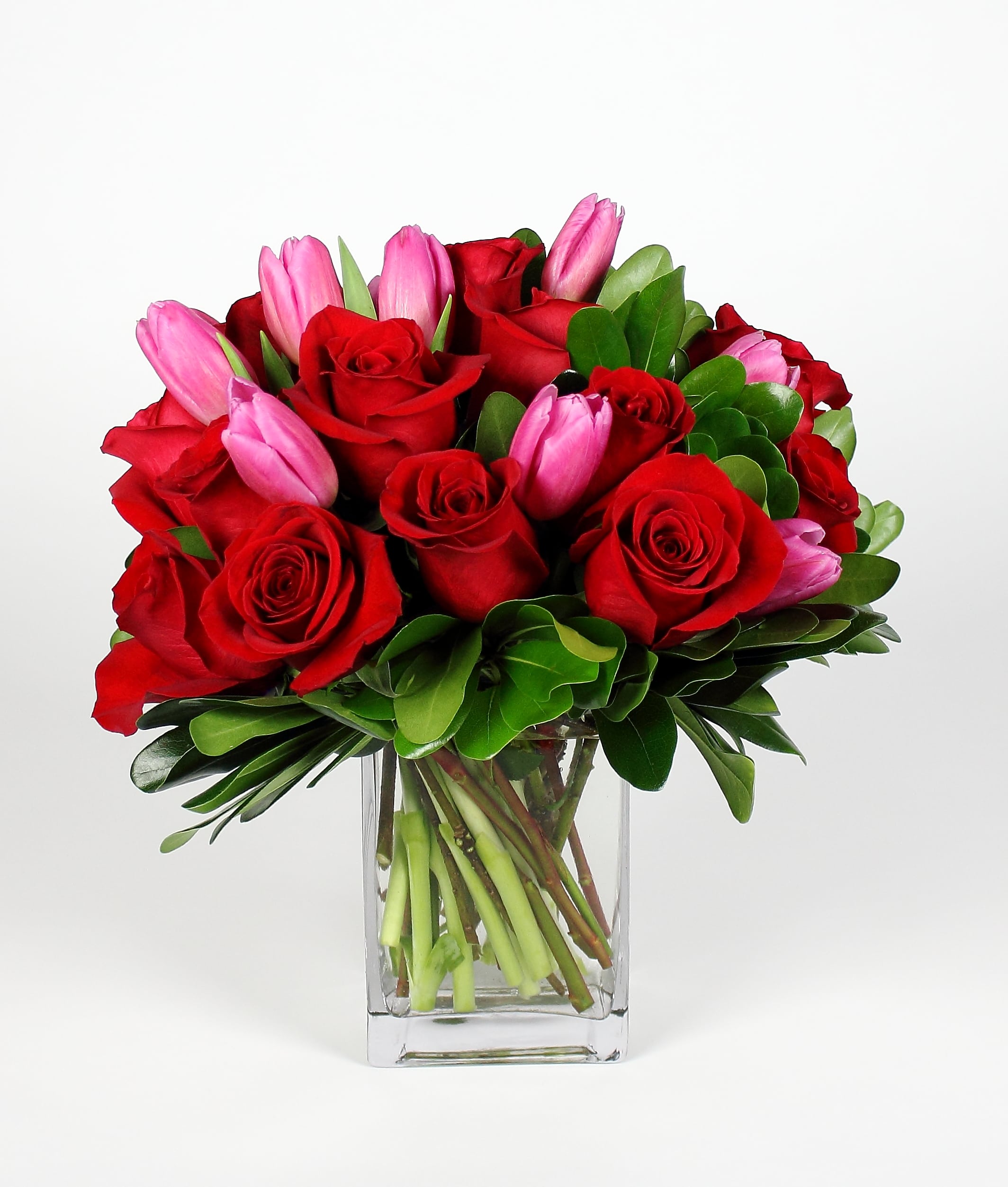 Red roses and pink tulips in a clear glass vase