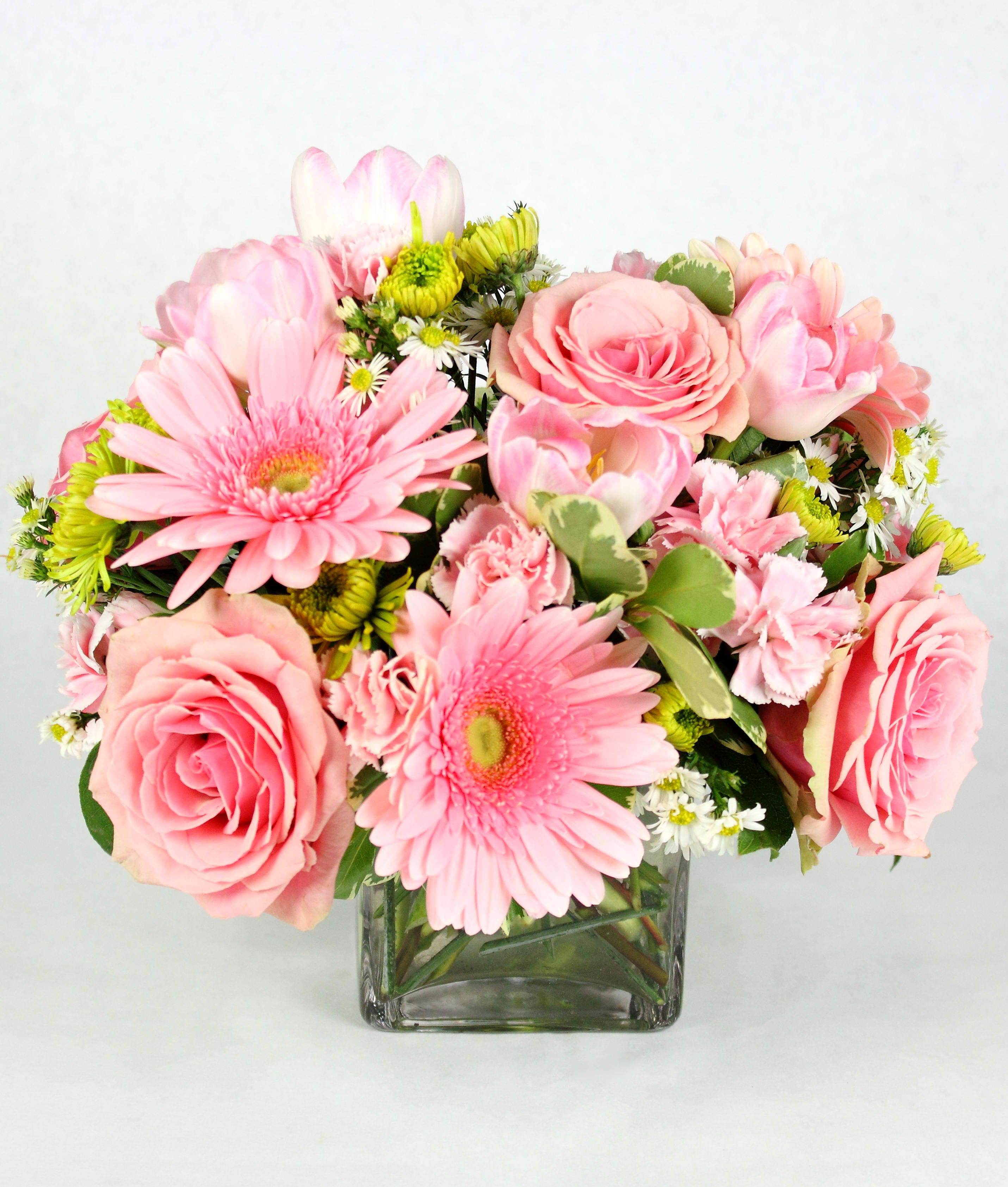 Pink roses and gerbera daisies in a square glass vase