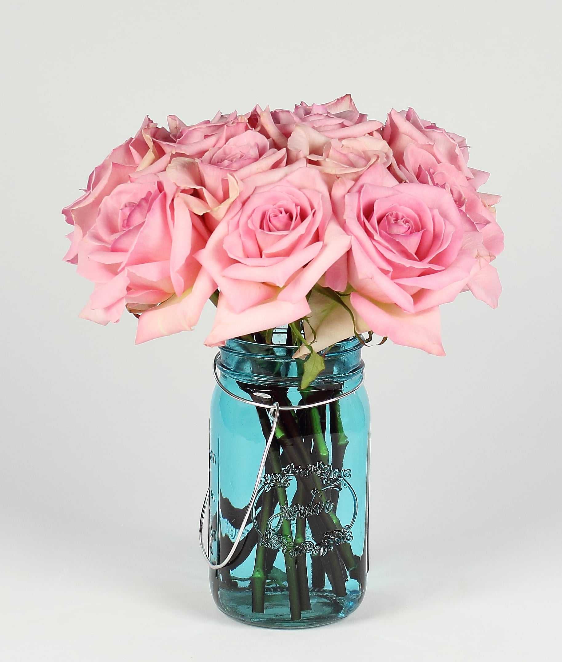 Pink roses arranged in a blue glass mason jar