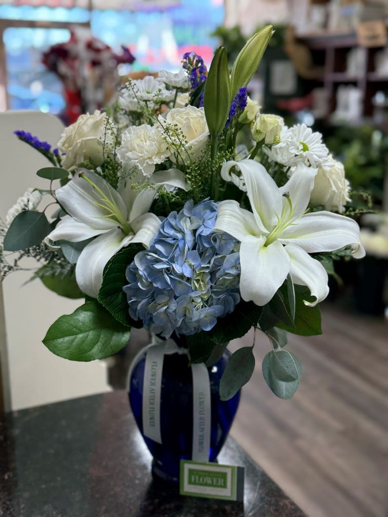 White lilies and blue hydrangea in a blue vase