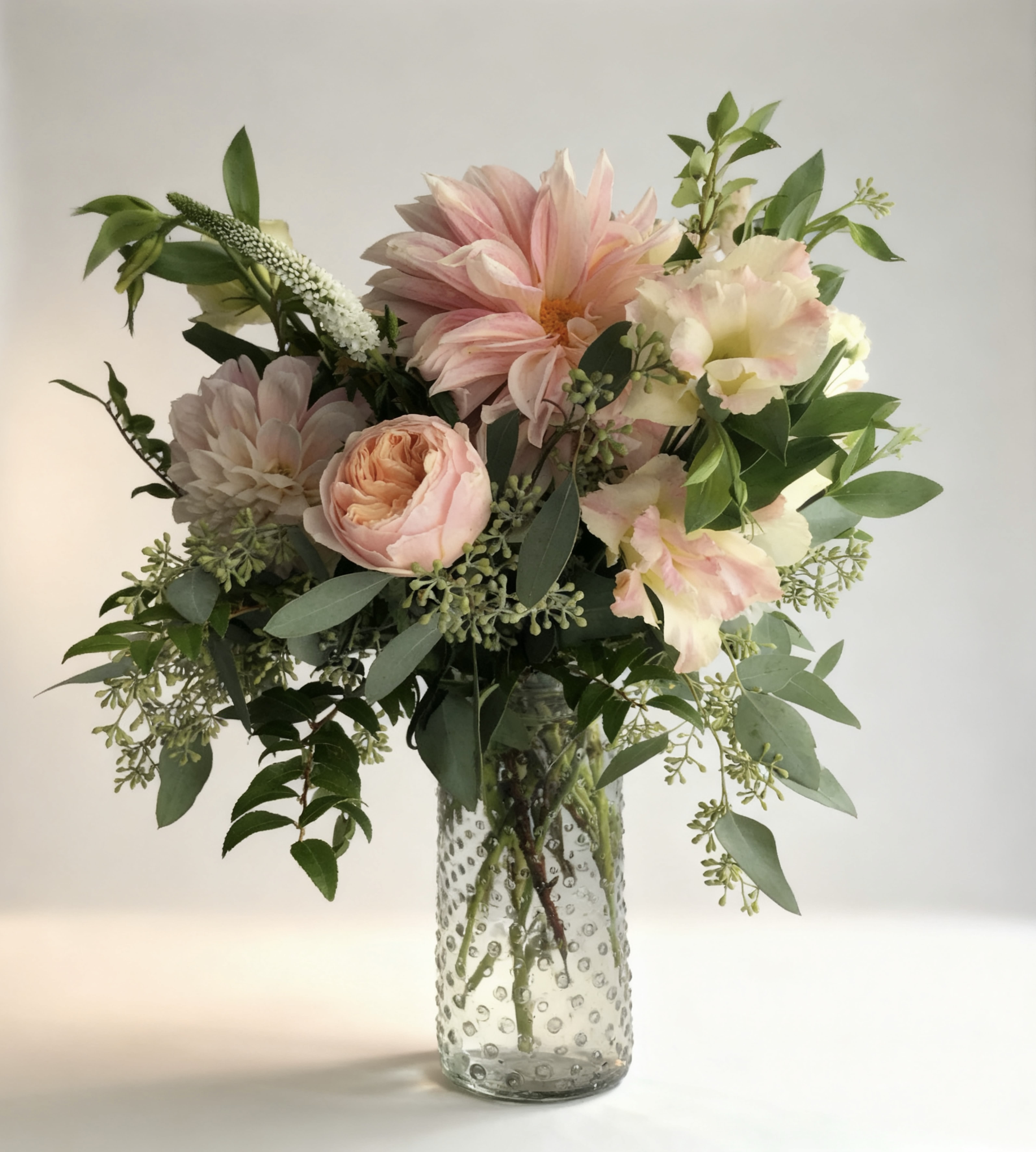 Pink and cream flowers in a clear textured glass vase
