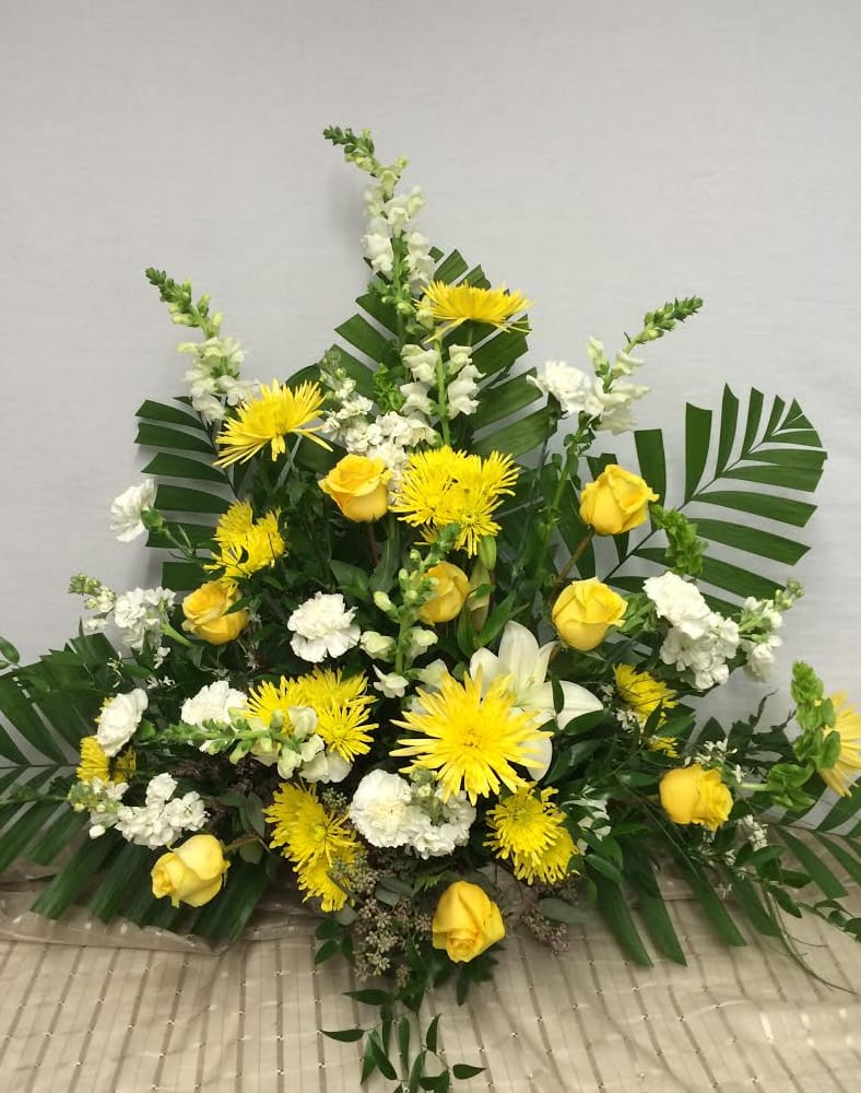 Yellow roses and white flowers in a large standing arrangement