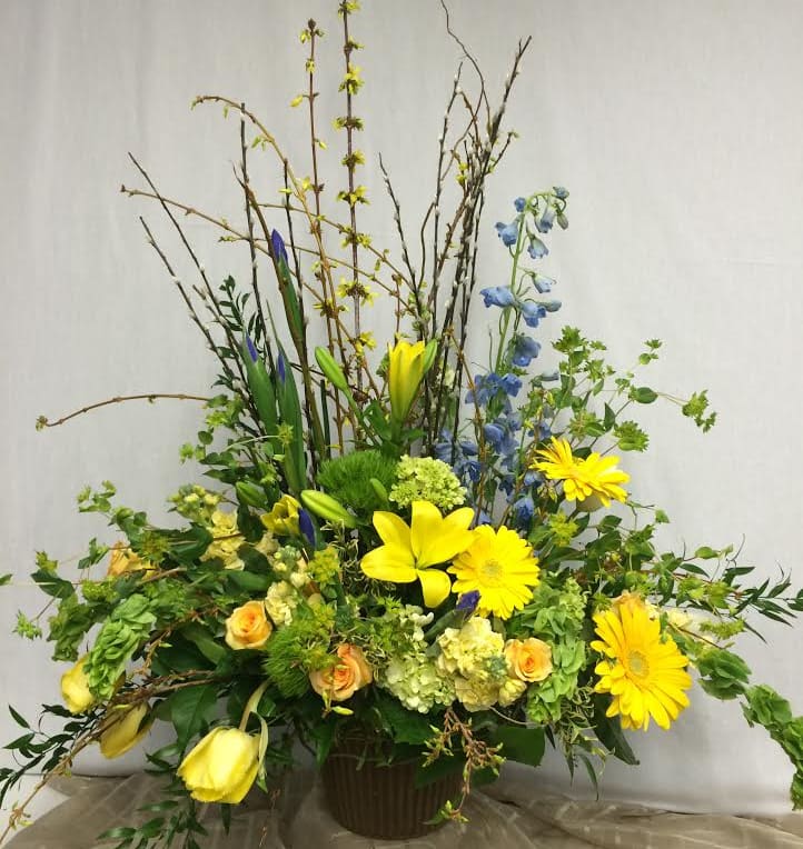 Tall mixed flower arrangement with yellow lilies and gerbera daisies in a vase