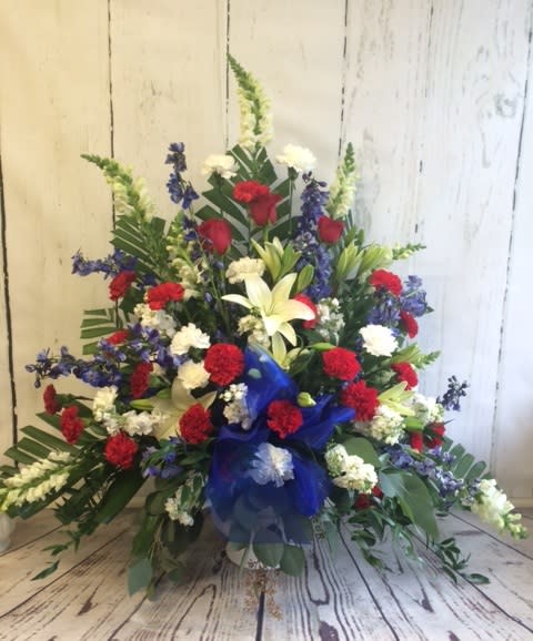 Large floral spray with red, white, and blue flowers in a blue ribbon wrap