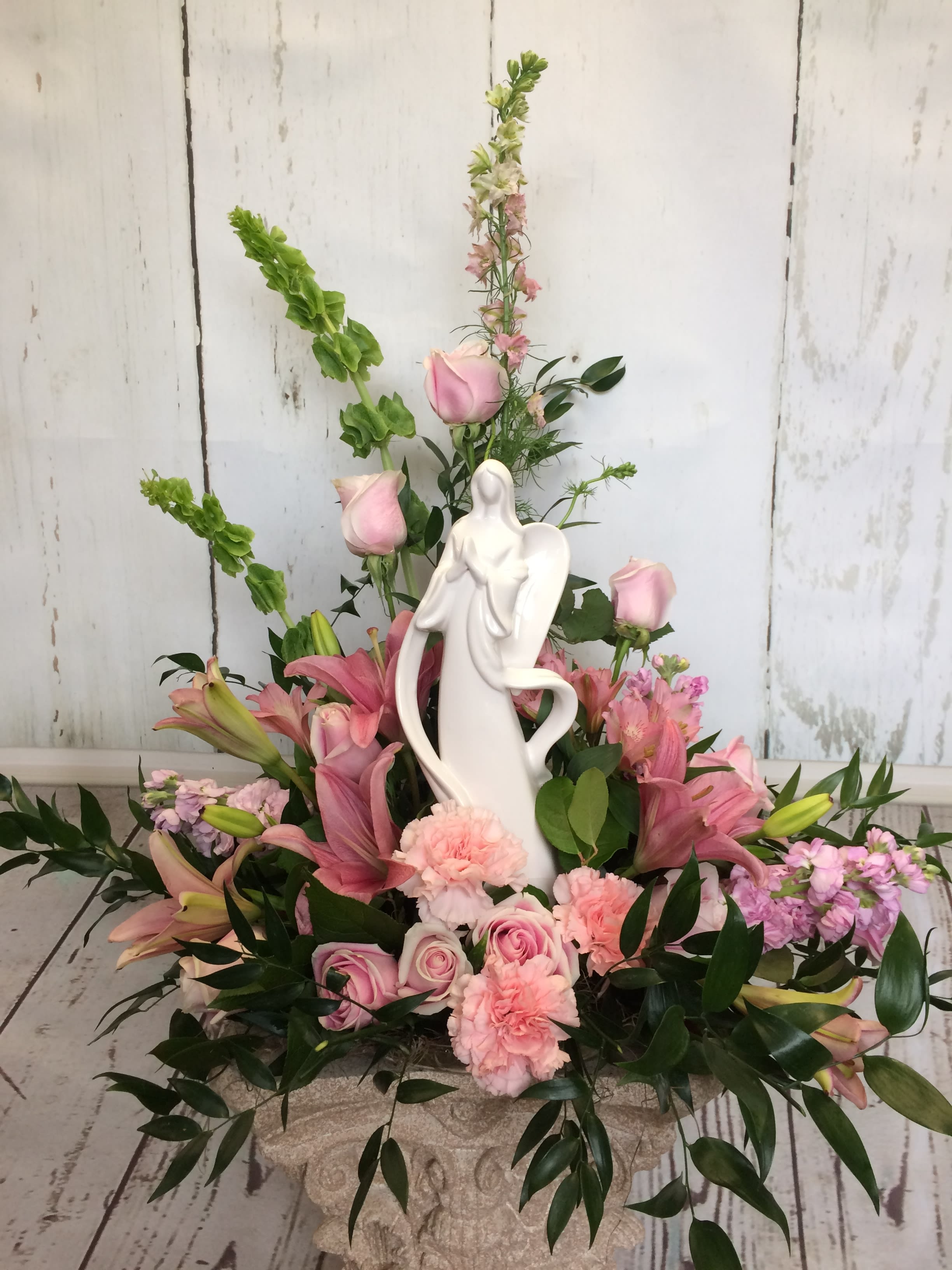 Pink floral arrangement with a white angel figurine centerpiece
